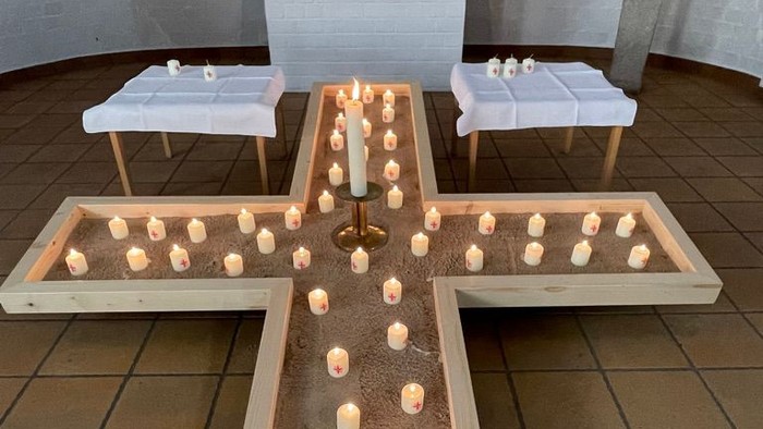 Ein Holzkreuz mit vielen Kerzen in einer Kirche