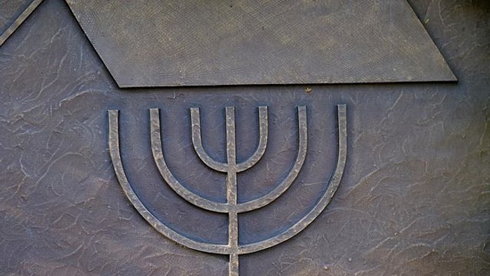 Metallene Menora mit sieben Armen auf einer strukturierten, messingfarbenen Oberfläche