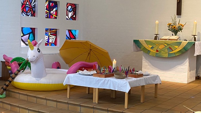 Ein bunter Raum mit einem Einhorn, Regenschirm und einem Tisch mit Kerzen und Blumen.
