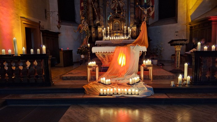 In der Kirche steht ein Altar mit vielen brennenden Kerzen und einer Statue.