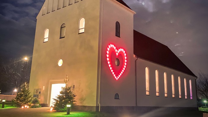 En kirke med et rødt hjerte lys på fasaden