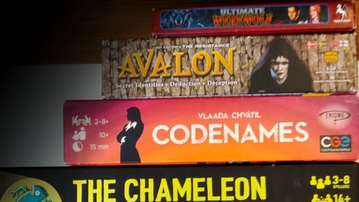 En samling brætspil, herunder Codenames, Kameleonen, Nonner på Flugt og Magic Maze, på en hylde.