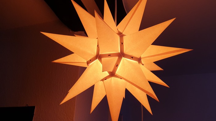 Ein leuchtender, sternförmiger Papierlaternenhimmel an der Decke.