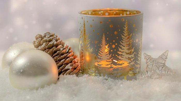 En julelyst med skovmotiv og omgivet af glitrende pynt og snø.