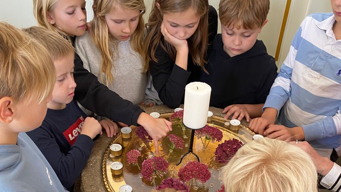 Børn samlede sig omkring et bord med en kage og lys.
