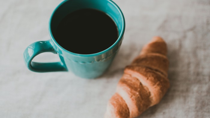 En blå tekop og en smørrebrød på marmorplade
