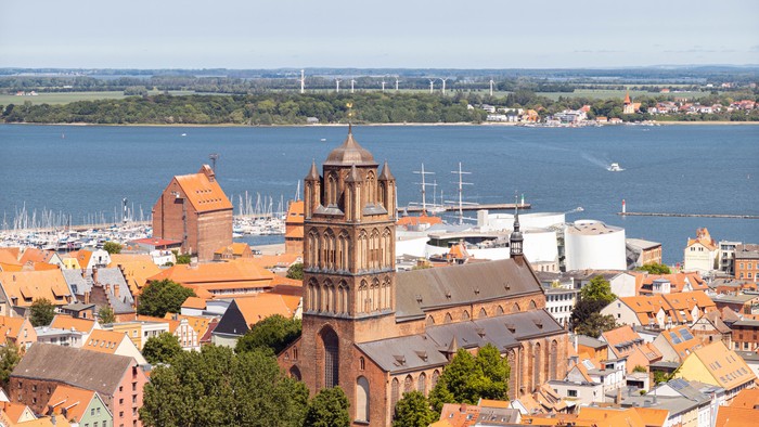 Die Stadt mit einem hohen Kirchturm und einem Hafen im Hintergrund