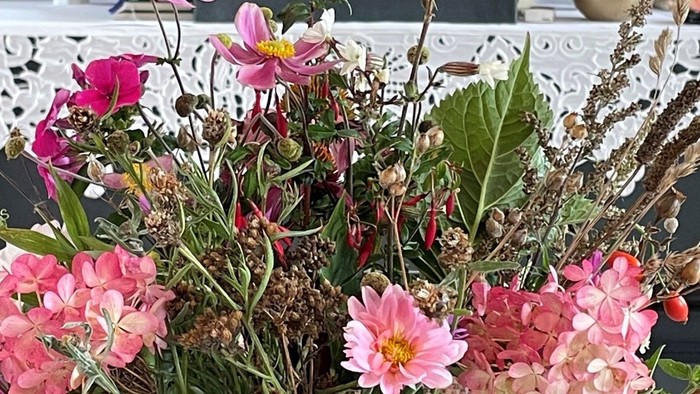 En stor blomsterstok med rosa og hvide blomster på bord med bog.