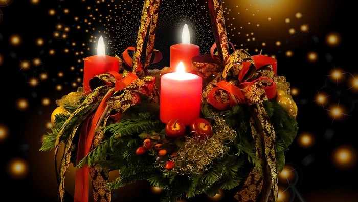 En hængende julelyst med tre lysende røde lys og grønne blomster.