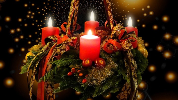 En hængende julelyst med tre lysende røde lys og grønne blomster.