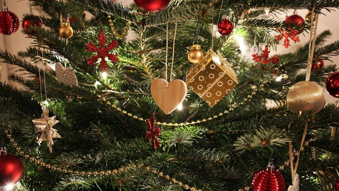 En juletree med røde og guld glasboller og forskellige pynt.