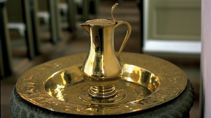 Guldfarvet kaffekanne på stenbænk i kirke