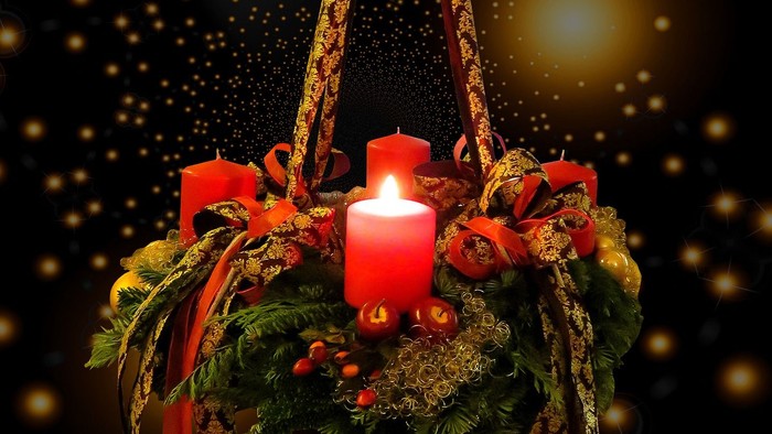 En hængende julelyst med grønne blomster og røde lys.