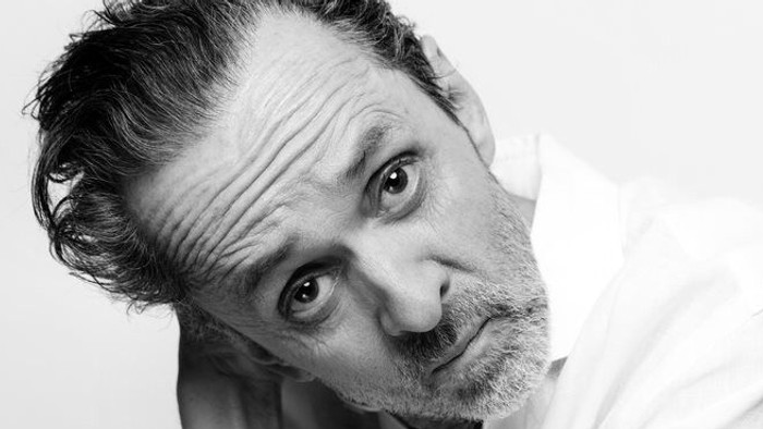 En mand med skæg, der bærer en hvid skjorte.