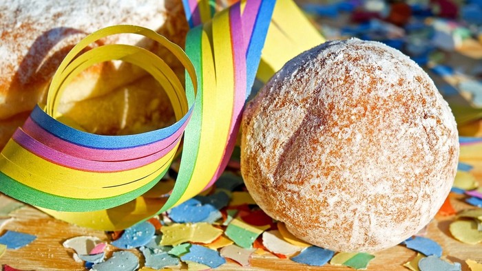 Ein Donut mit Zucker und bunte Streifen auf einem Holztisch