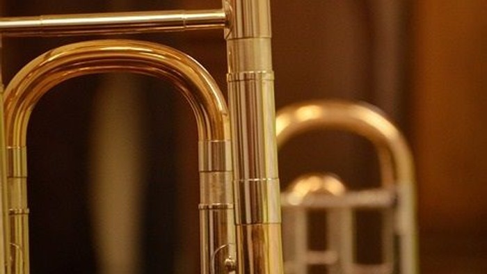 Drei goldfarbene Trompeten stehen nebeneinander.