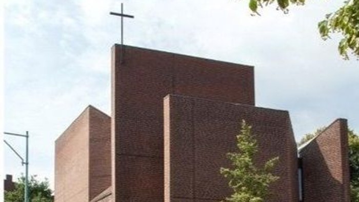 Das Bild zeigt eine moderne Kirche mit einem Kreuz auf dem Dach.