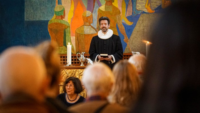 En præst holder en prædiken i en kirke, mens forsamlingen tilhører.