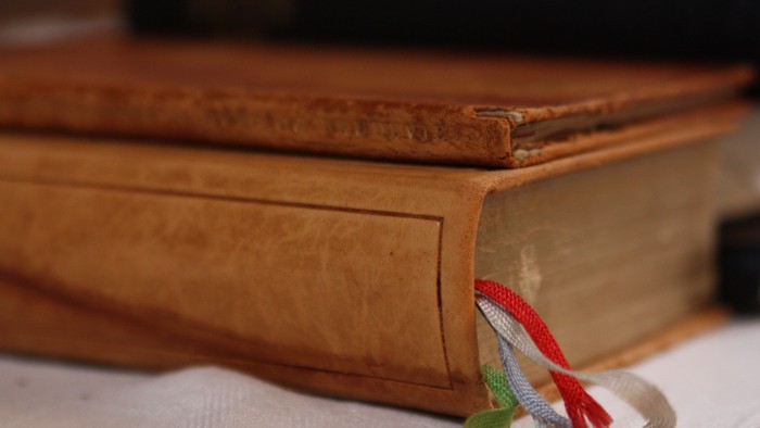 En stabel af gamle bøger med en bindebånd i røde og grønne farver.