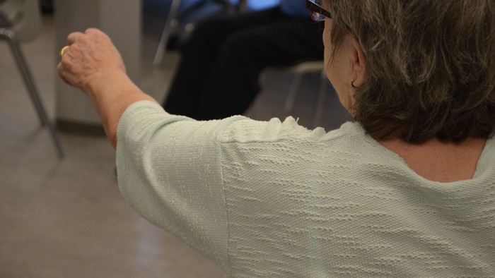 En kvinde med hårpudser og hvid trøje danser.