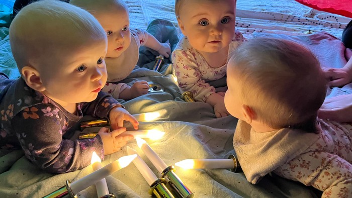 Fire små børn sidder på en matte og ser på en lysende lysstake.