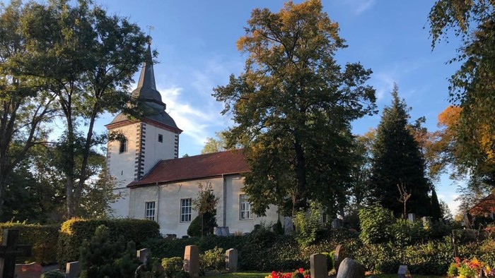 Weißes Kirchlein mit rotem Dach in parkähnlichem Garten