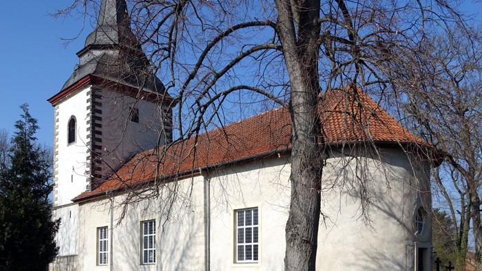Weiße Kirche mit rotem Dach und Turm unter blauem Himmel