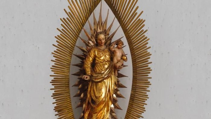 Goldene Marienstatue mit Strahlenkranz und Kerzenarrangement