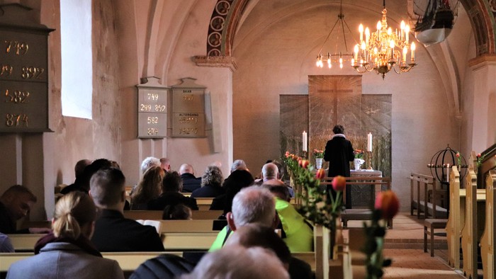 En kirke med folk, der sidder på bænkene og en præst ved alteret