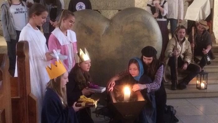 Kinder feiern in der Kirche Geburt von Jesus mit Kerzen und Kostümen