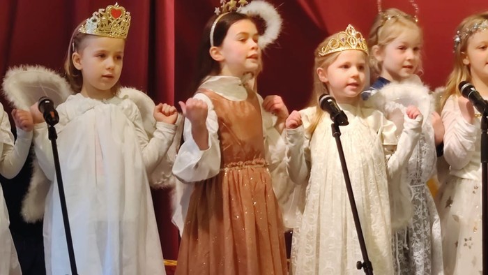 Kinder in festlichen Kleidern singen in einer Gruppe