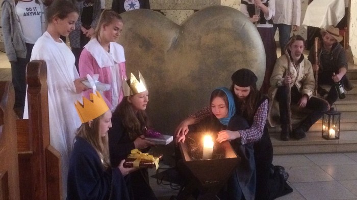 Kinder feiern in der Kirche Geburt von Jesus mit Kerzen und Kostümen