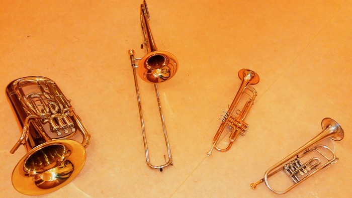 Vier verschiedene Blechblasinstrumente liegen auf einem Tisch