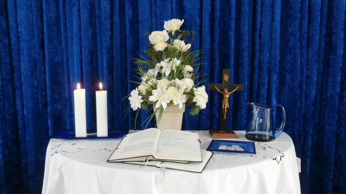 En altertavle med blomster, lysstake, bibel og kors