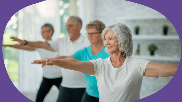 Gruppe von Senioren, die Dehn- oder Yogaübungen in einem hellen, indoor Fitnesskurs praktizieren.