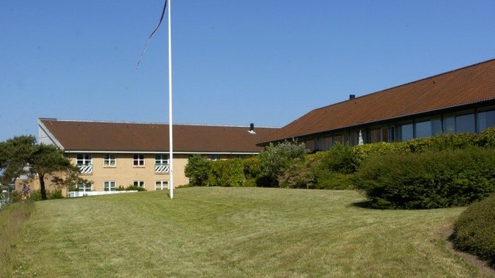 En stor bygning med rød tag og en flagstang foran