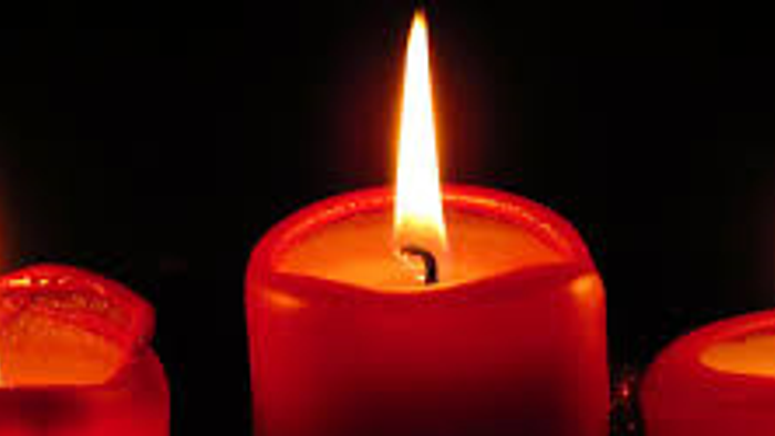 Tre røde lysekynder brænder i mørke.