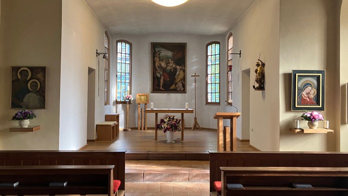 Kleine Kirche mit Holzbanken, Altarraum mit Kruzifix und Bildern