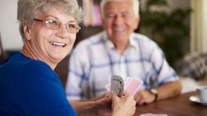Ein älteres Paar, das Karten spielt, lächelt und genießt die gemeinsame Zeit.