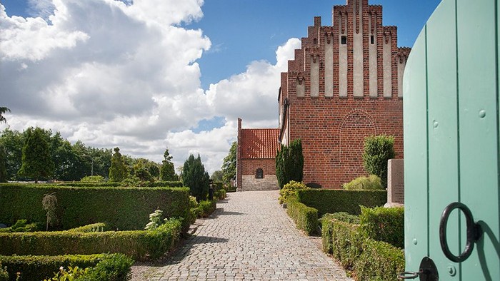 En smuk slot med mursten og tegl, omgivet af en grøn have og en sti.