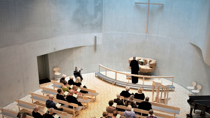 En lille kirke med træbænke og en præst ved alteret