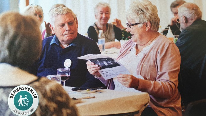 Mennesker samlet omkring et bord diskuterer et dokument.