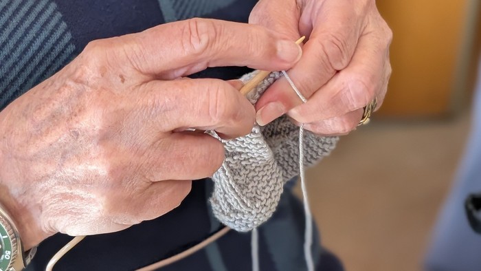 En person sitter og stråler en graig trøje.