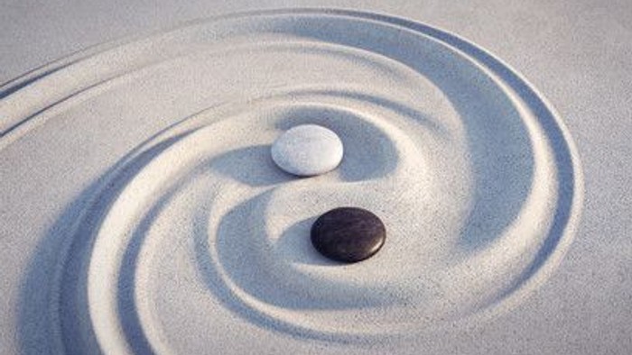 Zwei Steine in Sandspirale, eine in Weiß, die andere in Schwarz