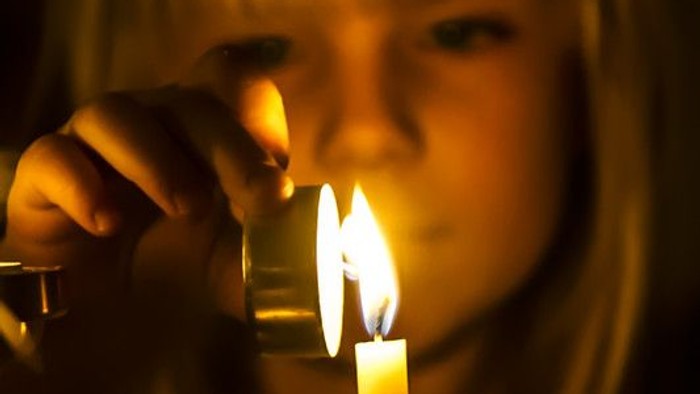 En pige blæser et lys ud på en kage.