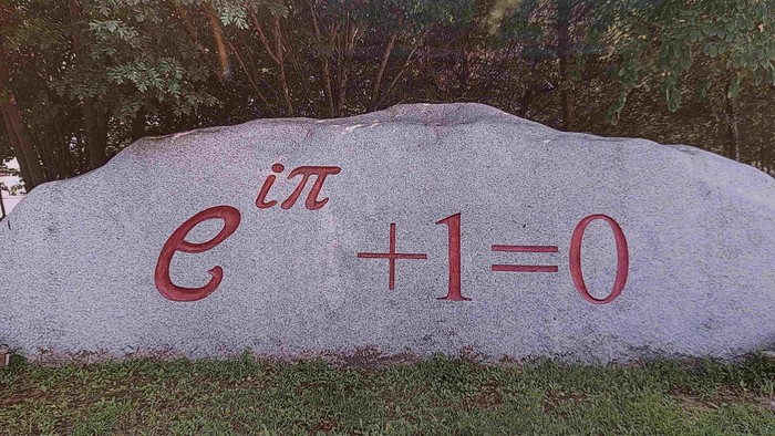 Ein großer Fels, der im Freien mit der berühmten Eulerschen Identität \( e^{i\pi} + 1 = 0 \) eingraviert ist.