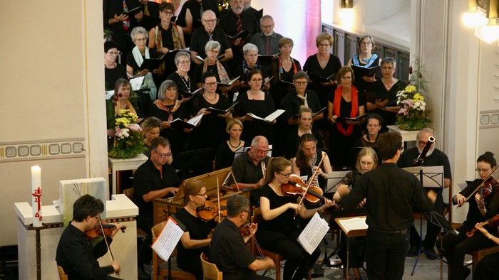 Ein großer Chor und Orchester proben in einem Saal