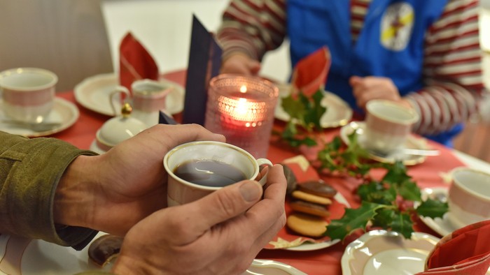 Eine Person hält eine Tasse Kaffee an einem festlich gedeckten Tisch.