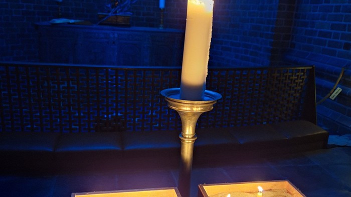 Religiøst helligdom oplyst af stearinlys med korsfæstelse og tændte lys