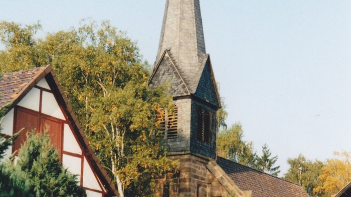 Kirche mit hohem Kirchturm und Kreuz an der Spitze.